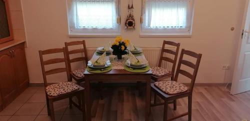 een eettafel met 4 stoelen en een tafel met bloemen bij Szaffária Apartman Kehidakustány in Kehidakustány