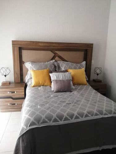 1 dormitorio con 1 cama grande con almohadas amarillas en Casa como nueva, cómoda y tranquila, en Guadalajara