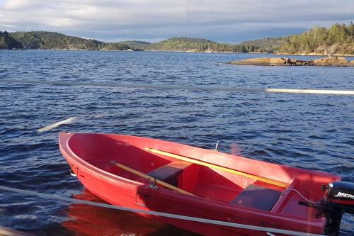 a red boat sitting on a body of water at Sommerferie egen båt ,jacuzzi, bålpanne og grill,ukesleie i juli in Asker
