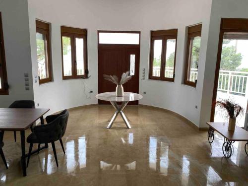 a room with a table and chairs and windows at Kallithea Residence in Koskinou