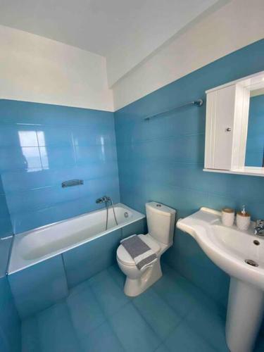 a blue bathroom with a toilet and a sink at Kallithea Residence in Koskinou