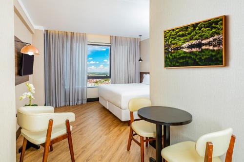 um quarto de hotel com uma cama, uma mesa e cadeiras em NH HOTEL FEIRA DE SANTANA em Feira de Santana