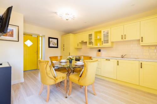 a kitchen with a dining table and yellow chairs at Bective Stud Apartments in Navan