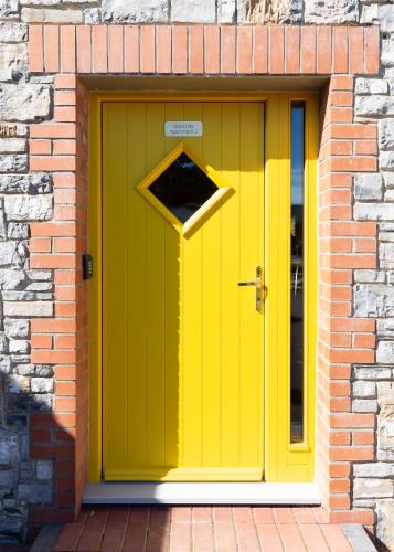a yellow door on a brick building with a brick wall at Bective Stud Apartments in Navan