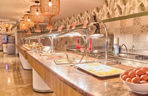 a kitchen with a long counter with a bunch of food at Leonardo Hotel Fuengirola Costa del Sol in Fuengirola