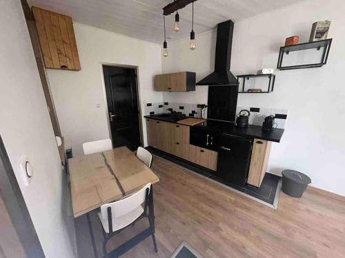 a kitchen with a wooden table and a dining room at Le Refuge de la Gravière in Charleville-Mézières