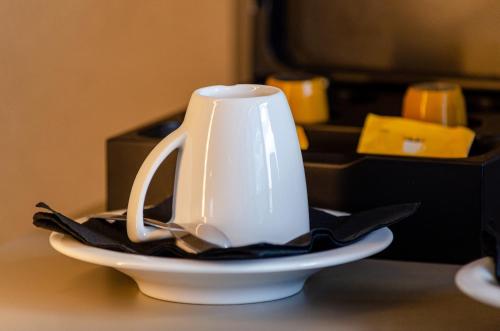 a white tea kettle on a plate on a table at OMID Saldanha Hotel in Lisbon