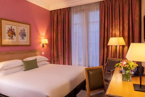 a hotel room with a bed and a desk with a desk sidx sidx at Le Littré in Paris