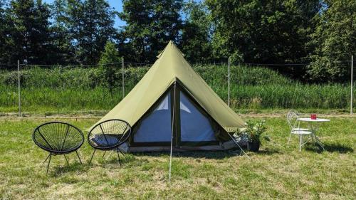a tent with two chairs and a table in a field at Campingspots to put on your own tent with or without electricity, with no bed for 12 euro or 25 euro and 2 furnished glampingtents for minimum 75 euro in a green and peaceful environment between Antwerp and Brussels 