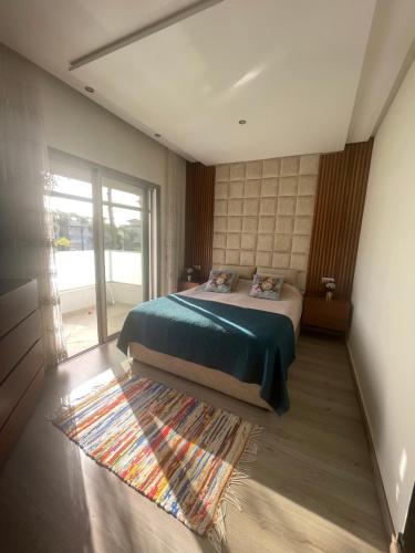 a bedroom with a bed with a green blanket and a rug at BEAU TRIPLEX EN RESIDENCE in Skhirat