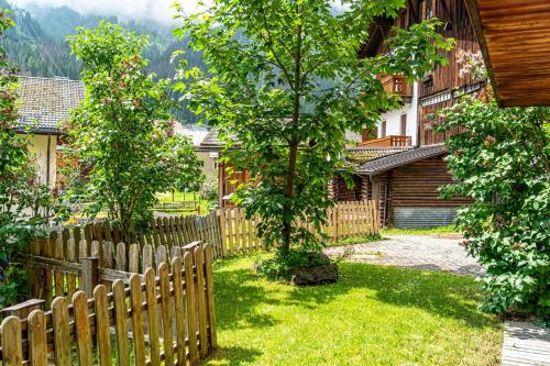 una recinzione in legno in un cortile alberato e in una casa di Tabià La Stua ad Arabba