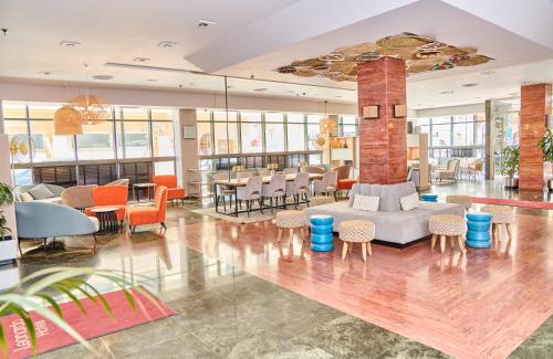 a lobby with a couch and tables and chairs at Leonardo Hotel Fuengirola Costa del Sol in Fuengirola