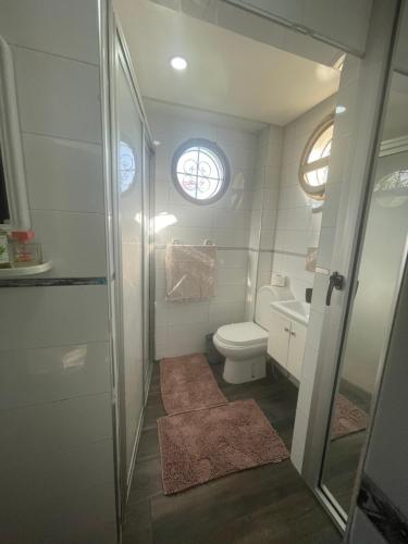 a bathroom with a toilet and a sink and two windows at BEAU TRIPLEX EN RESIDENCE in Skhirat