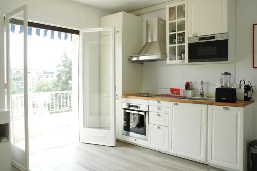 uma cozinha com armários brancos e uma grande janela em Good location, sunny terrace, beach and shops at 4 mn em Antibes