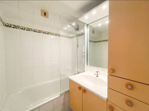 uma casa de banho com um lavatório, uma banheira e um espelho. em Apparement T3 avec vue mer em Roquebrune-sur-Argens
