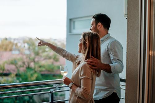 a man and a woman standing on a balcony with a glass of wine at Penthouse with Balcony in Luton