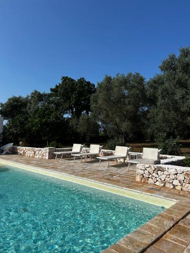 a swimming pool with lounge chairs and a table at trullo Giardino Sotto La Luna in Ceglie Messapica