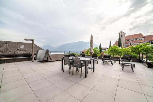 a patio with a table and chairs on a roof at Schenna Chalet - Apt Dora in Schenna