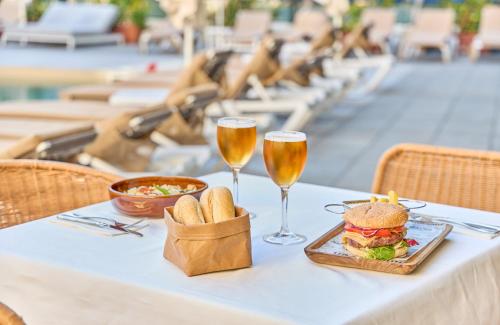 a table with a sandwich and two glasses of beer at Leonardo Hotel Fuengirola Costa del Sol in Fuengirola