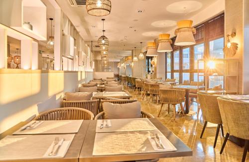 a dining room with tables and chairs and windows at Leonardo Hotel Fuengirola Costa del Sol in Fuengirola