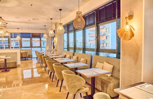 a restaurant with tables and chairs and windows at Leonardo Hotel Fuengirola Costa del Sol in Fuengirola