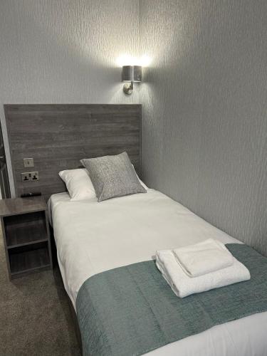 a bedroom with a large white bed with a wooden headboard at Arrandale Guest House in Edinburgh