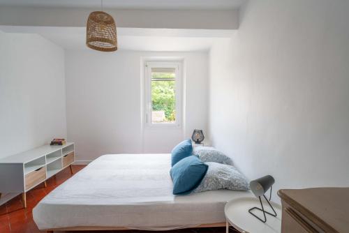 een witte slaapkamer met een groot bed met blauwe kussens bij La maison d'à côté in Carpentras