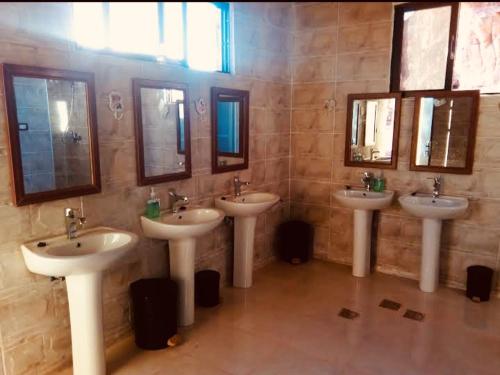 a bathroom with three sinks and mirrors on the wall at Wadi rum Rozana camp in Wadi Rum