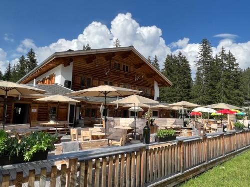 ein Gebäude mit Tischen, Stühlen und Sonnenschirmen in der Unterkunft Erezsässhütte in Klosters