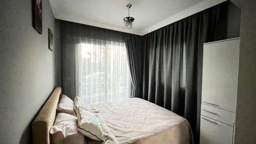 een kleine slaapkamer met een bed en een raam bij Elit Yaşam Site 1-Bedroom flat with pool in Fethiye