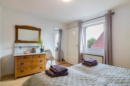 ein Schlafzimmer mit einem Bett, einer Kommode und einem Fenster in der Unterkunft Landhausappartment in Bermatingen