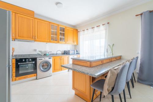 a kitchen with wooden cabinets and a counter top at The Sunset 1 Bed Flat short walk Armação beach in Armação de Pêra