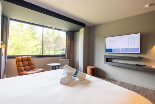 a hotel room with a bed and a flat screen tv at Miura in Voglans