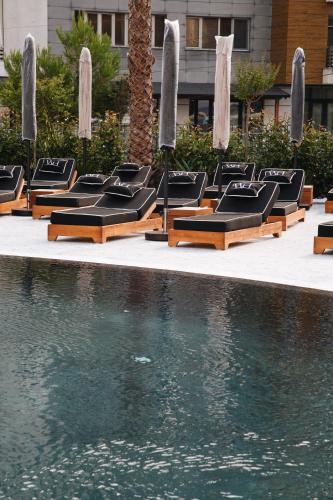 a row of lounge chairs next to a swimming pool at White Hill Hotel, SPA & Conferences in Durrës