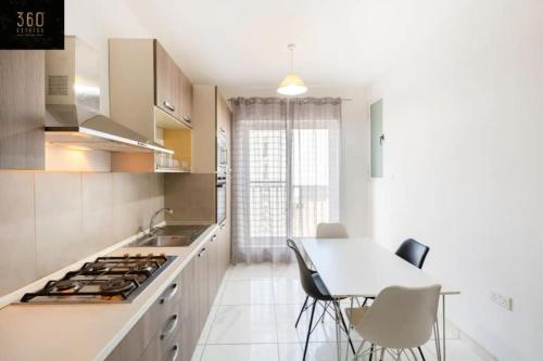 een keuken met een tafel en stoelen en een fornuis bij Beautiful, central home with all amenities & WIFI by 360 Estates in Tal-Pietà