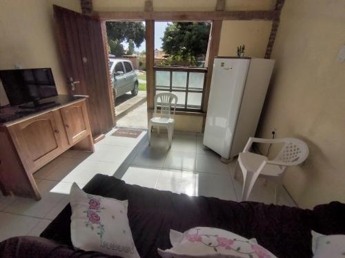 a living room with a couch and a refrigerator at Chalé Brisa do Mar in Santa Cruz Cabrália