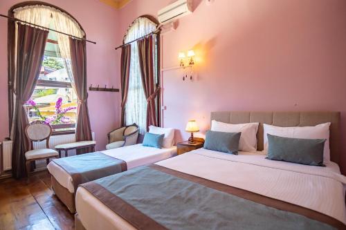 two beds in a room with pink walls and windows at Büyükada Anastasia Meziki History Mansion in Buyukada