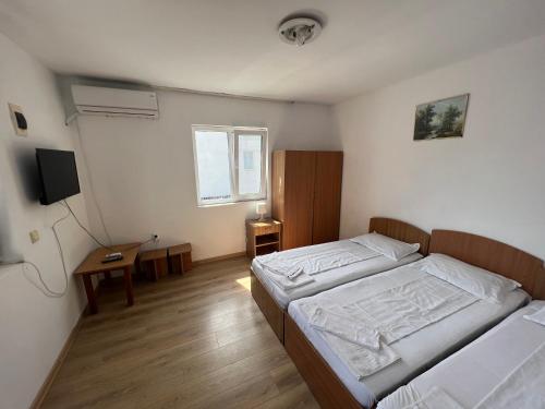 ein Schlafzimmer mit zwei Betten und einem Schreibtisch und einem Fernseher in der Unterkunft Mario Residence in Costinești