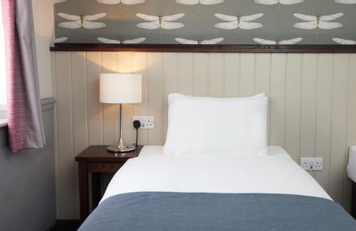 1 dormitorio con cama, lámpara y papel pintado de mariposa en Charnwood Arms, en Coalville