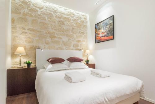 - une chambre avec un lit blanc et un mur en pierre dans l'établissement MONTORGUEIL CHARMING APARTMENT, à Paris