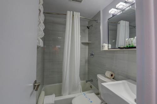 a bathroom with a white shower curtain and a toilet at Le Voyageur - a Red Collection Hotel in Wildwood