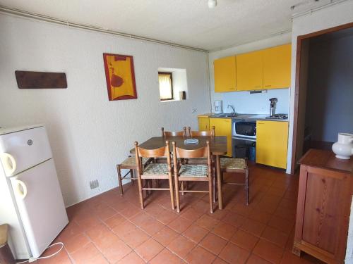 uma cozinha com mesa, cadeiras e armários amarelos em Bienvenue en Transition 55 - Les Gardettes em Najac