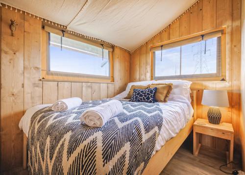 a bed in a room with wooden walls and two windows at Folly Farm Holiday Park in Kilgetty