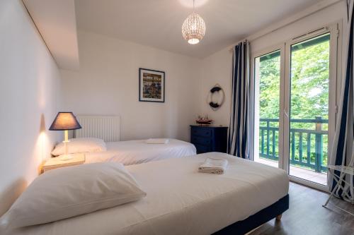 a bedroom with two beds and a balcony at Ziburu Mendi - Appartement Calme, Vue Mer, Parking - WiFi in Ciboure