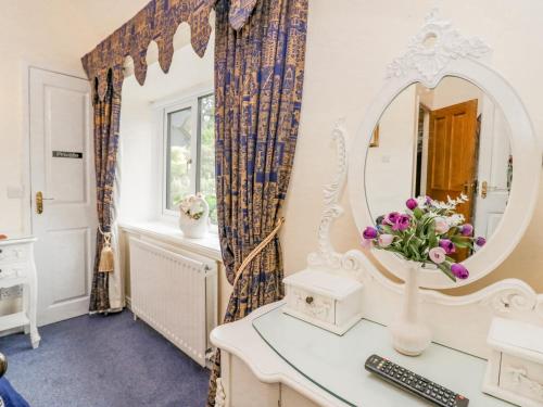 a bathroom with a mirror and a desk with a vase of flowers at Storrs Lodge in Windermere