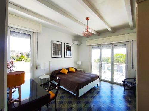 Schlafzimmer mit einem Bett, einem Schreibtisch und Fenstern in der Unterkunft Villa Orizzonte sullo Jonio in Avola