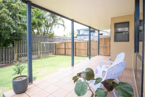 a patio with two white chairs and a plant at Stones Throw To Shelly Beach, Pet Friendly! in Caloundra