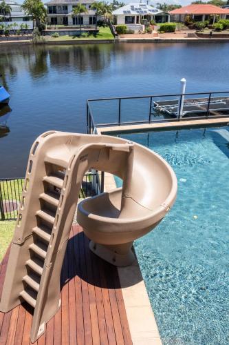 a slide sitting on a deck next to a swimming pool at Parrearra Paradise On The Water With Water Slide in Parrearra