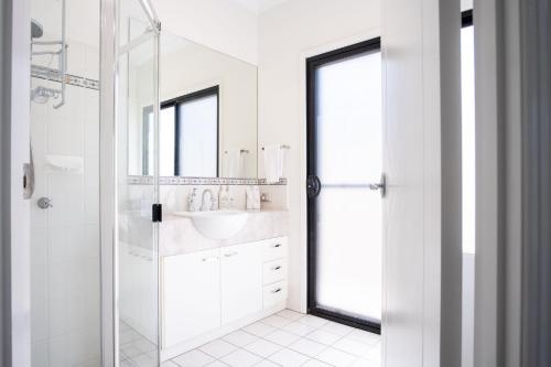 a white bathroom with a sink and a shower at Parrearra Paradise On The Water With Water Slide in Parrearra