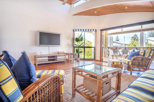 a living room with couches and a tv at Coastal Getaway Across From Dicky Beach in Caloundra
